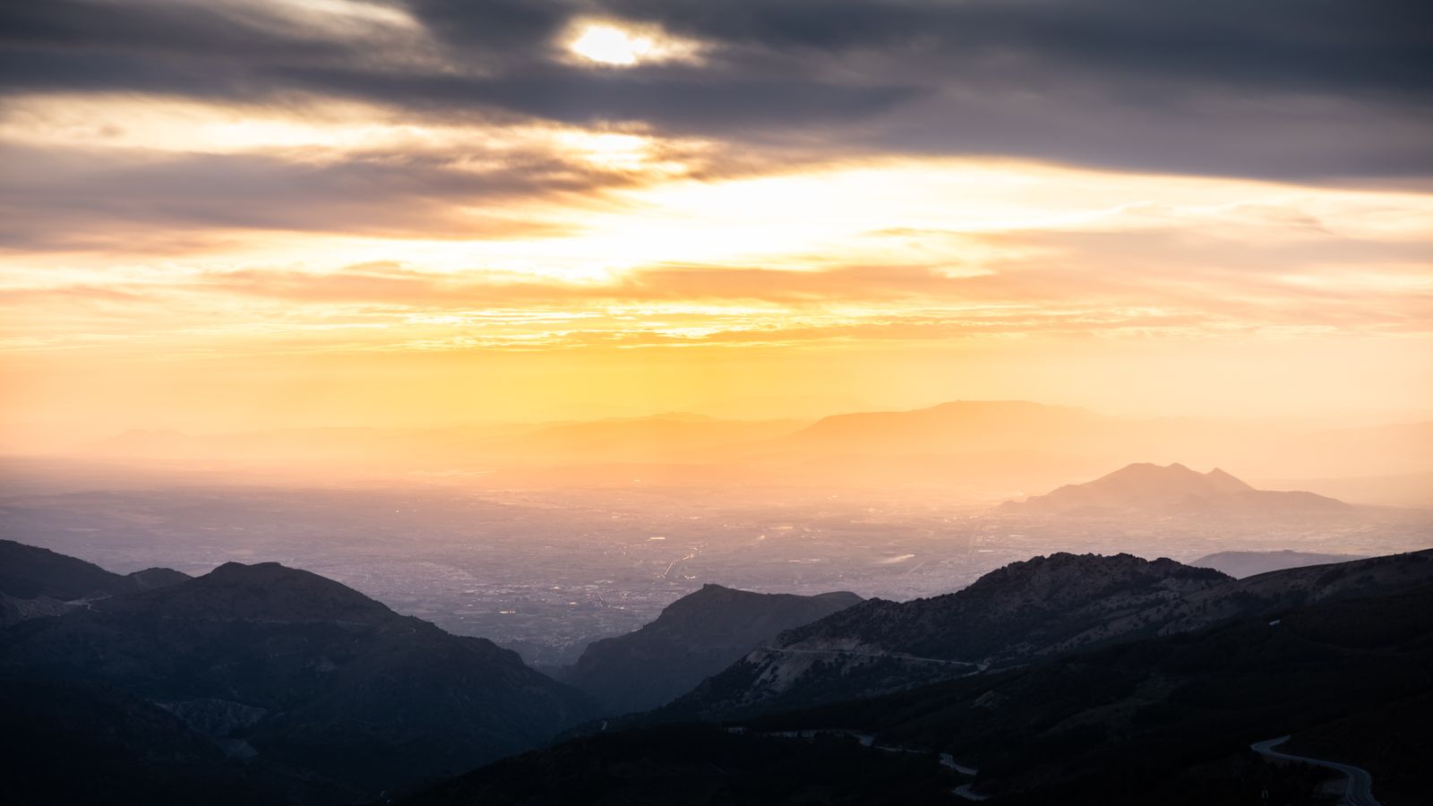 Sunrise over a mountain range with mist filling the valley below
