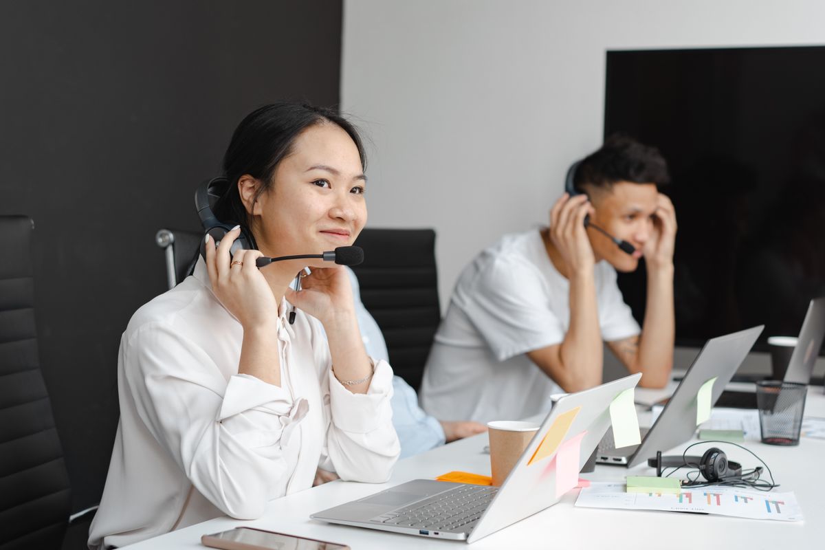 Two people wearing headsets at a support desk