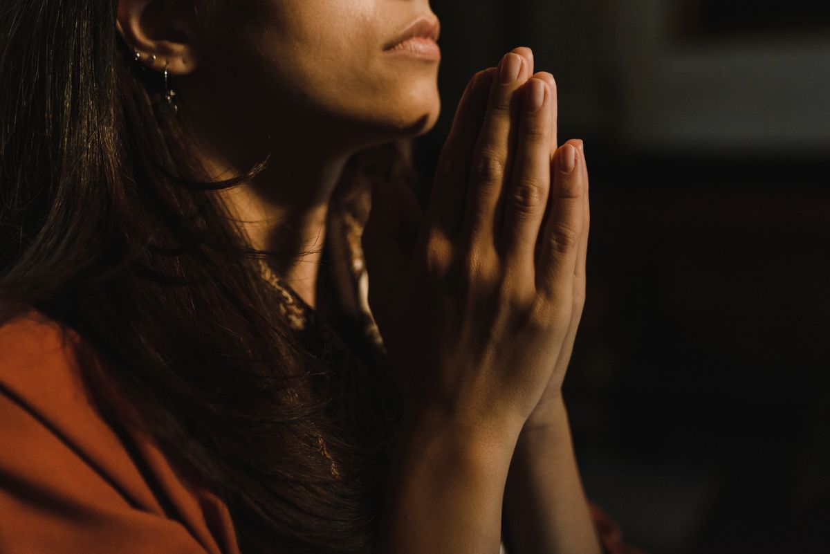 A woman with her hands together in prayer