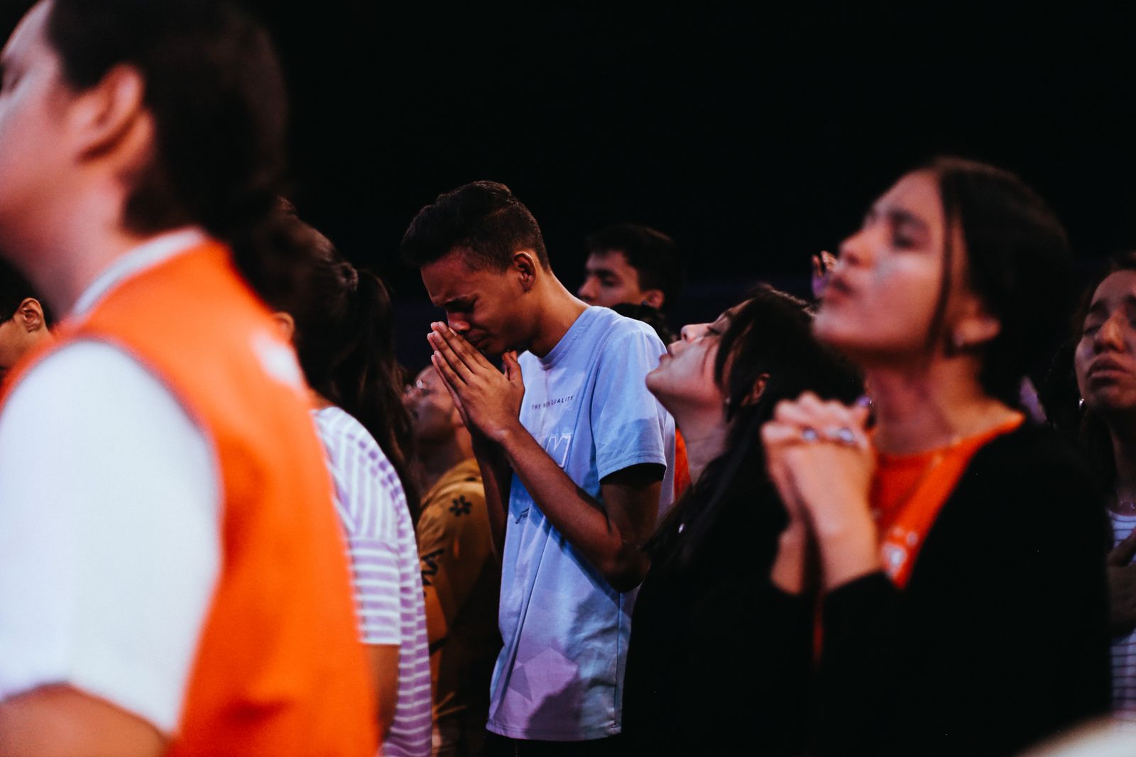 A group of young people praying together at a gathering