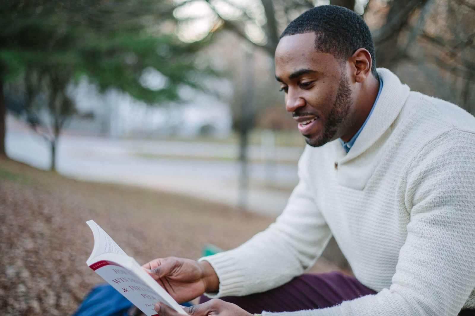 A man reading outdoors, book open in his hands