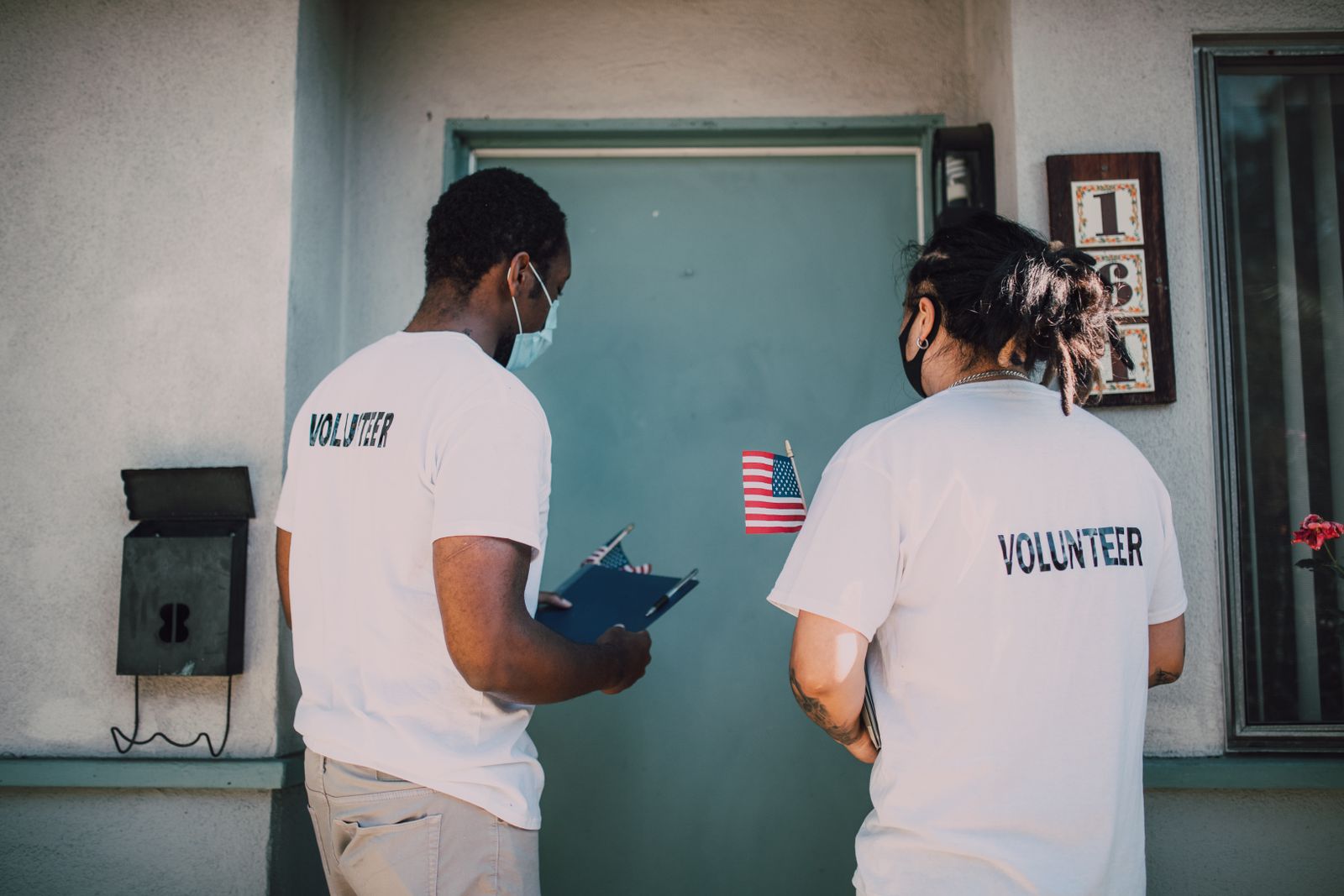 Two volunteers in branded shirts working together at a doorway